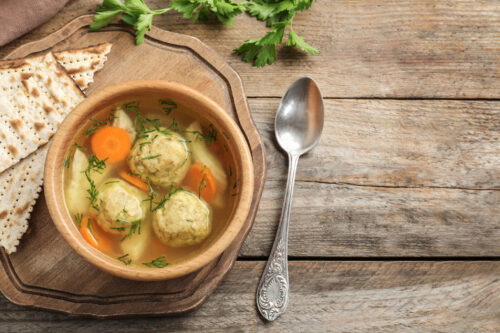 Flat lay composition with Jewish matzoh balls soup on wooden table. Space for text